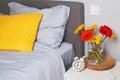 Bedroom interior with bright decorative pillow on the bed and brigh flowers on the nightstand. Royalty Free Stock Photo
