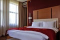 Bedroom interior. Double bed with pillows, duvet and red bedspread.