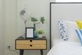 Bedroom interior with striped pillow on bed and bedside table lamp with picture frame on it.