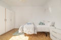 Bedroom with a large double bed with a white wardrobe with mirrors and slatted parquet floors laid in a checkerboard pattern Royalty Free Stock Photo