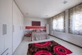 Bedroom with large queen bed with grey, gray side-by-side wardrobe and garish rug