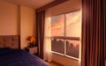 Bedroom in the morning with morning sunlight through glass window with opened curtains. Luxury bed in modern apartment in the city Royalty Free Stock Photo