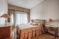 A bedroom with quality antique wooden furniture with a mesh headboard and a balcony with curtains and sheers