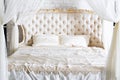 Bedroom in soft light colors. Big comfortable four poster double bed in elegant classic bedroom. Luxury white with gold interior Royalty Free Stock Photo