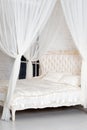 Bedroom in soft light colors. Big comfortable four poster double bed in elegant classic bedroom. Luxury white with gold interior d Royalty Free Stock Photo