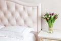 Bedroom in soft light colors. Vase of colorful tulips in light cozy bedroom interior Royalty Free Stock Photo