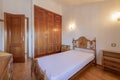 Bedroom with a three-section built-in wardrobe with sapelly wood doors, vintage wooden furniture and a matching wooden access door Royalty Free Stock Photo