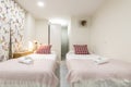 bedroom with two beds with pink blankets, red cushions, rolled towels Royalty Free Stock Photo