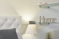 Bedroom with white capitone headboard, glass shelves with messages