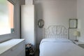 bedroom with a white metal headboard and stacked drawers and cabinets silver framed mirrors and a white bedspread