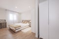 Bedroom with wooden headboard, white hanging tables, beige cushions