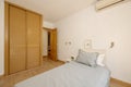 bedroom with a youth bed with gray cushions and a built-in wardrobe with Venetian-style wooden doors Royalty Free Stock Photo