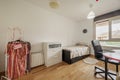 Bedroom with a youthful bed, a study table with a chair on wheels, a white chest Royalty Free Stock Photo