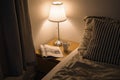 bedside table with a magazine, a cup of tea, a lamp with warm light by the bed. cozy room interior. Scandinavian style. Royalty Free Stock Photo