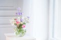Bedside table, vase with rose and lilac flowers.  White background. Copy space Royalty Free Stock Photo