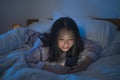 Bedtime lifestyle high angle portrait of young beautiful and happy sweet Asian Chinese girl with in headband and pajamas enjoying