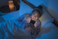 Bedtime lifestyle high angle portrait of young beautiful and happy sweet Asian Chinese girl in headband and pajamas enjoying with