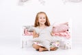 Bedtime. Little girl near bed with pink linen with pillow in the form of a star in her hands in white bedroom with handmade Royalty Free Stock Photo