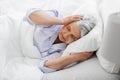 annoyed senior woman with headache in bed at home