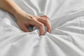 Hand of woman squeezing white bed sheet