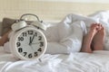 Bedtime sleep with alarm clock at noon or midnight time on bed in bedroom for world lazy day and healthy resting life balance