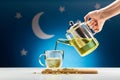 hand with teapot pouring chamomile tea at night Royalty Free Stock Photo