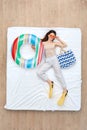 Bedtime. Young girl in flippers and sunglasses lying on bed top view with swim ring and bag smiling happy Royalty Free Stock Photo