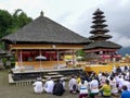 BEDUGUL, INDONESIA MARCH, 15, 2018: hindu worshipers sit in a courtyard of pura danu bratan temple in bali
