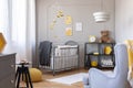 Bee decorations in a kid room interior with a crib, armchair and teddy bear. Royalty Free Stock Photo