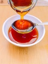 Bee honey rawhoney sweet food natural sweetener ingredient floral nectar pouring on spoon and a bowl closeup image photo