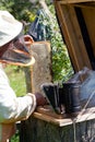 Bee-keeper smokes bees from a beehive a smoke by means