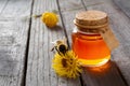 Bee perches next to honey bottle on wooden table