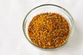 Bee pollen granules in a glass bowl on white background. Superfood. Copy space Royalty Free Stock Photo