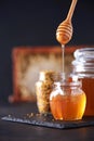 Bee pollen granules, honey jar with wooden dropper, honeycomb on dark backdrop. Copy space. Autumn harvest concept