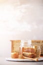 Bee pollen granules, honey jar with wooden dropper, honeycomb on grey backdrop. Copy space. Autumn harvest concept