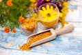 Bee pollen in wooden scoop with yellow flower in plastic glass Royalty Free Stock Photo