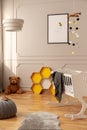 Bee poster, honeycombs, teddy bear on the floor and crib in a toddler room interior. Real photo