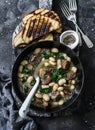 Beef, beans, spinach slow cooker stew in a pan on a wooden board on a dark background. Delicious homemade comfort food Royalty Free Stock Photo