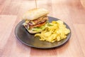 Beef burger with egg, cheese, bacon and lettuce inside a rustic bread and french fries on a black plate Royalty Free Stock Photo