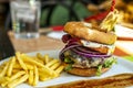 Beef burger with fried egg, crispy red onion rings, melted cheese, fried bacon, raw lettuce, tomato slices Royalty Free Stock Photo