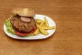 A beef burger with plenty of caramelized onion and a slice of foie gras and a garnish of home frie