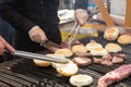 Beef burgers being grilled on food stall grill.