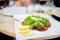 Beef carpaccio with salad, parmesan cheese and lemon slices served on a dish in a restaurant