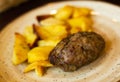 Beef cutlet with spinach garnished with baked potato wedges on white plate