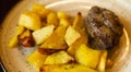 Beef cutlet with spinach garnished with baked potato wedges on white plate