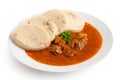 Beef goulash with bread dumplings and parsley garnish on white ceramic plate isolated on white Royalty Free Stock Photo