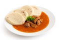 Beef goulash with bread dumplings and parsley garnish on white ceramic plate isolated on white Royalty Free Stock Photo