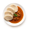 Beef goulash with bread dumplings and parsley garnish on white ceramic plate isolated on white. Top view Royalty Free Stock Photo