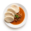 Beef goulash with bread dumplings and parsley garnish on white ceramic plate isolated on white. Top view Royalty Free Stock Photo