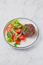 Beef hamburger with lettuce tomato salad on white plate, top view Royalty Free Stock Photo